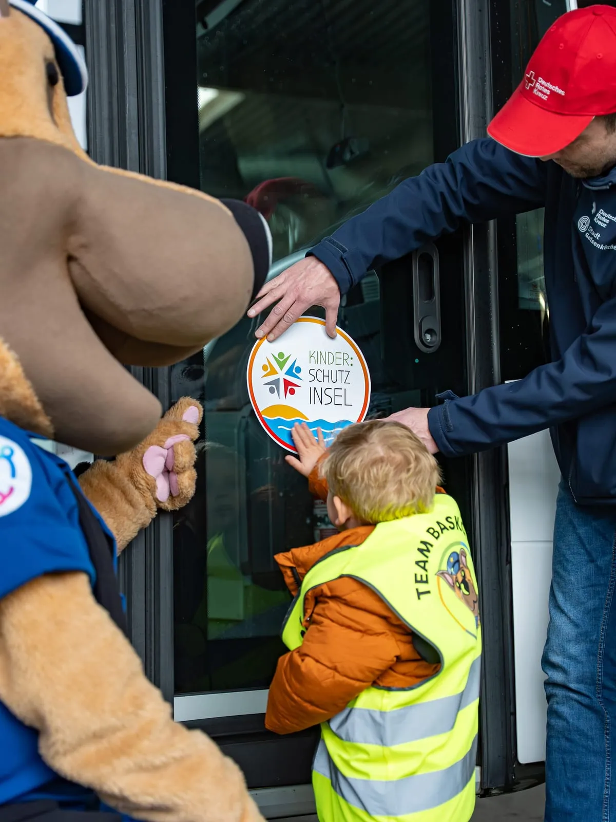 Maskottchen und Kind bei einer Aktion der Kinderschutzinsel